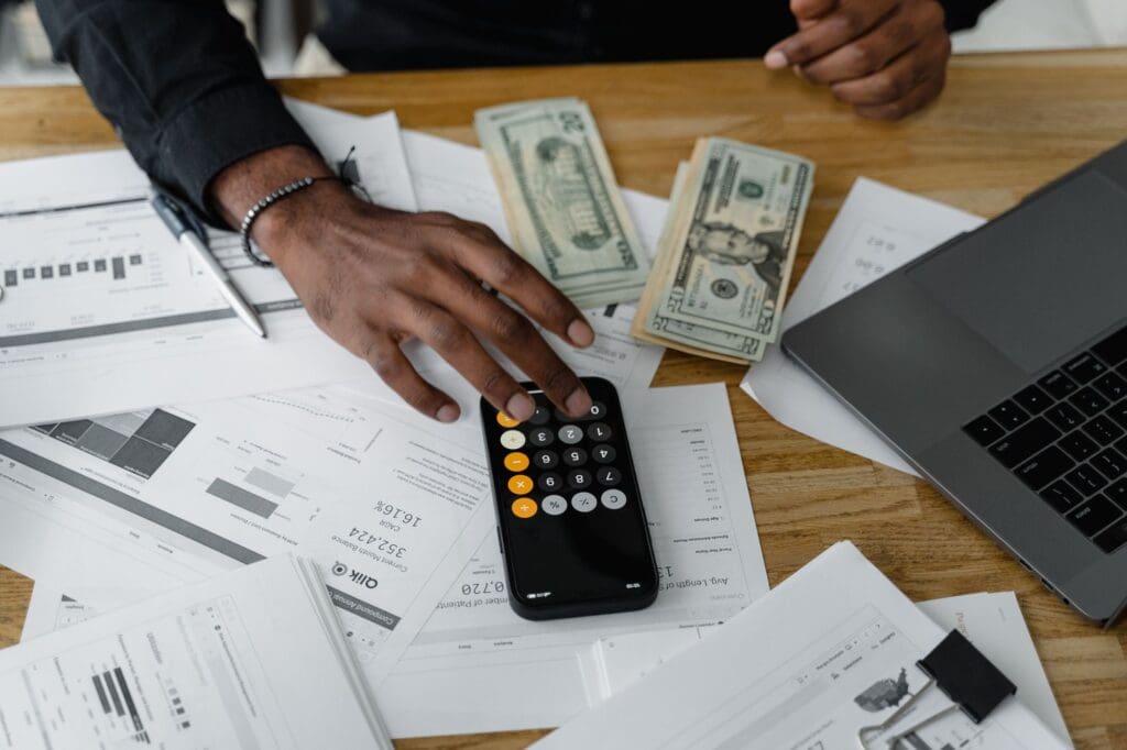 Man reviewing papers and calculating on his phone for Bookkeeping for Nonprofits